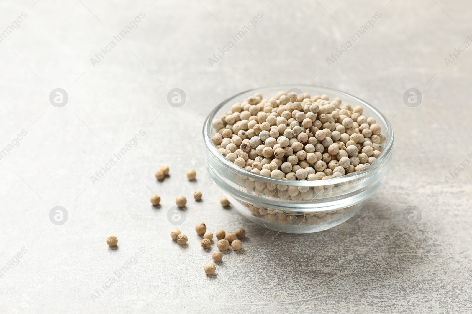 Photo of Aromatic spice. White pepper in bowl on light grey table, space for text