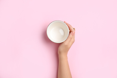 Woman with empty cup on light pink background, top view