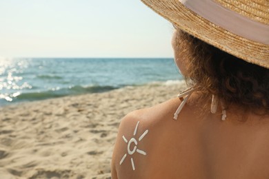 African American woman with sun protection cream on shoulder at beach, back view