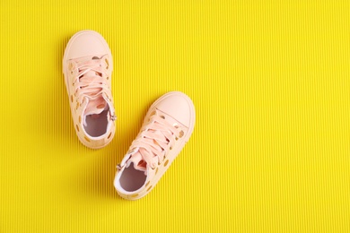 Photo of Pair of stylish child shoes on yellow background, flat lay. Space for text