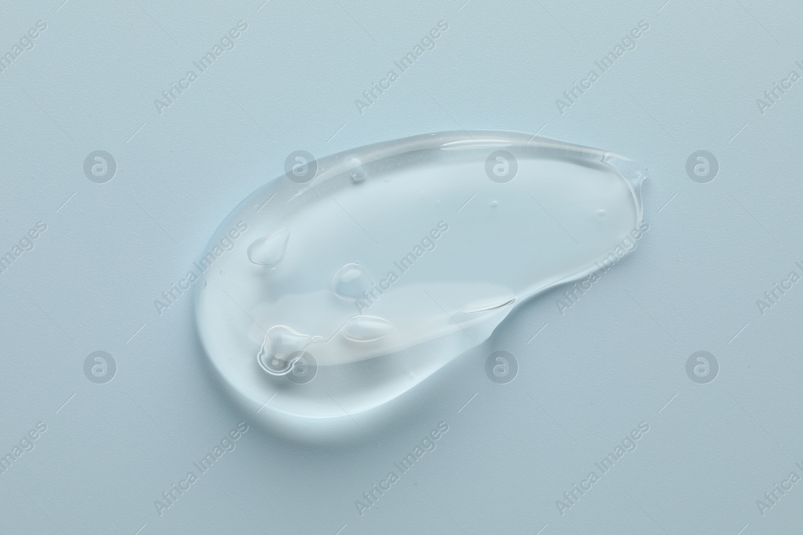 Photo of Smear of clear cosmetic gel on light blue background, top view