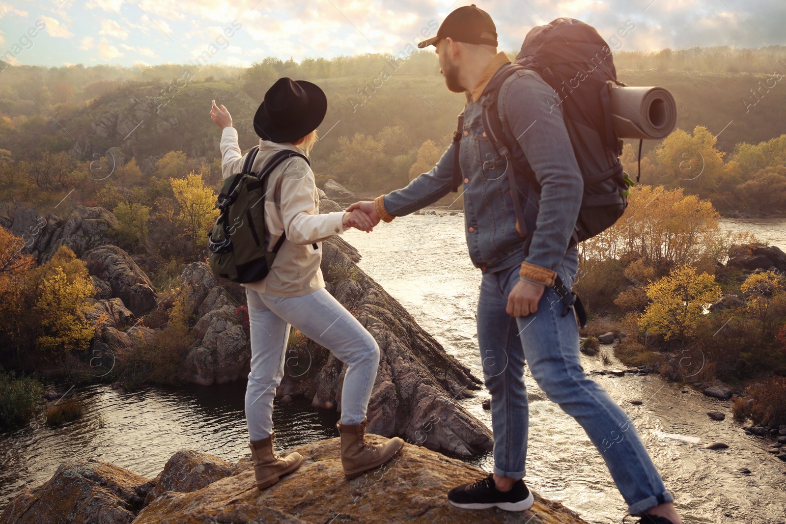 Photo of Couple of hikers with backpacks climbing up mountains