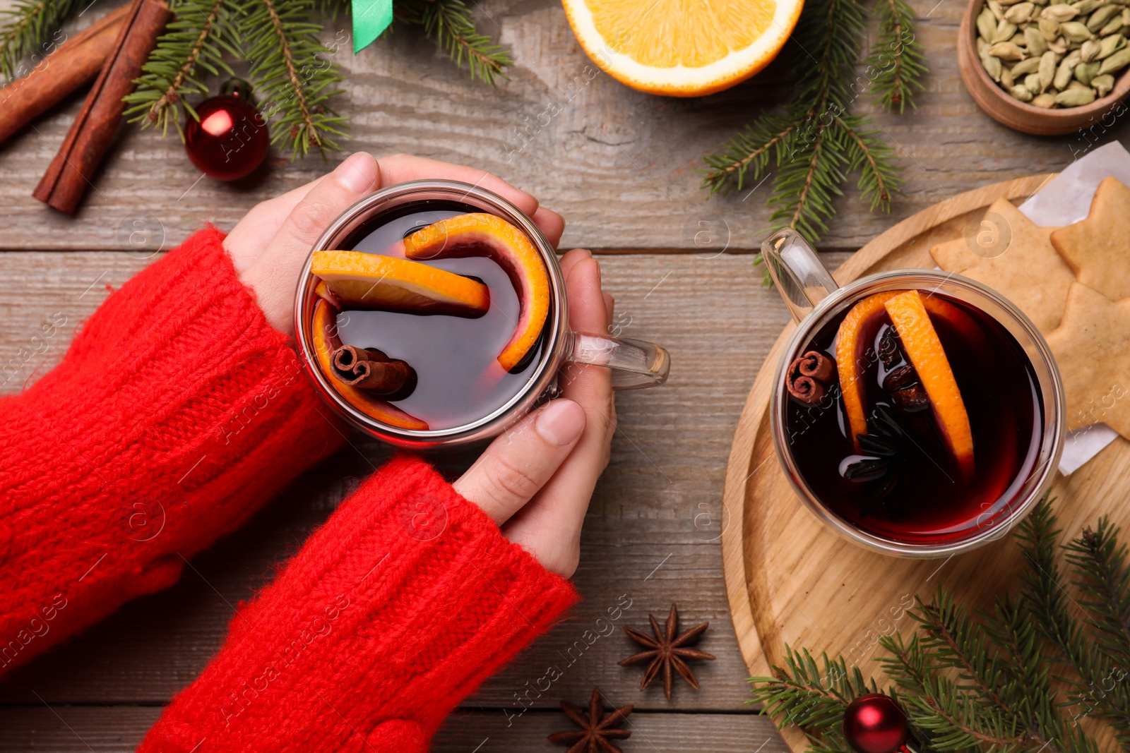 Photo of Woman with cup of mulled wine at wooden table, top view