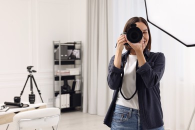 Photo of Young professional photographer taking picture in photo studio, space for text