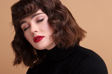 Portrait of beautiful young woman with wavy hairstyle on beige background