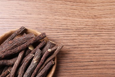 Photo of Dried sticks of liquorice root on wooden table, top view. Space for text