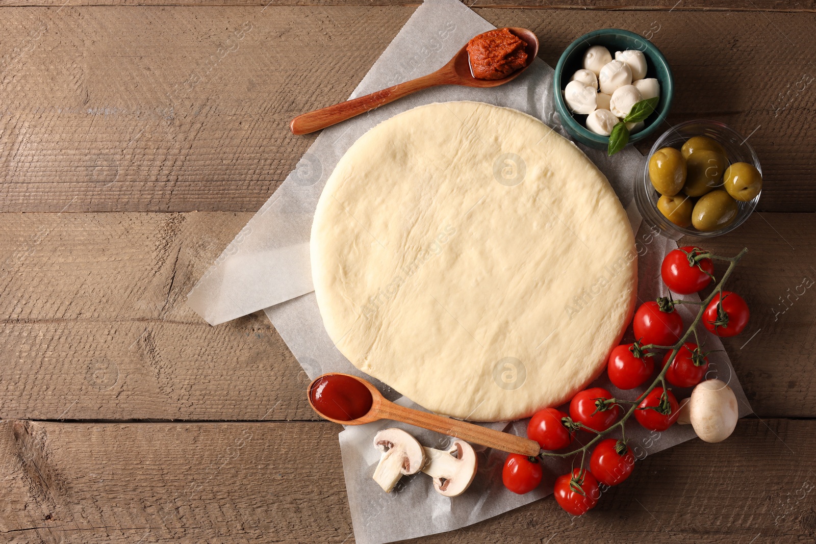 Photo of Pizza dough and products on wooden table, flat lay. Space for text