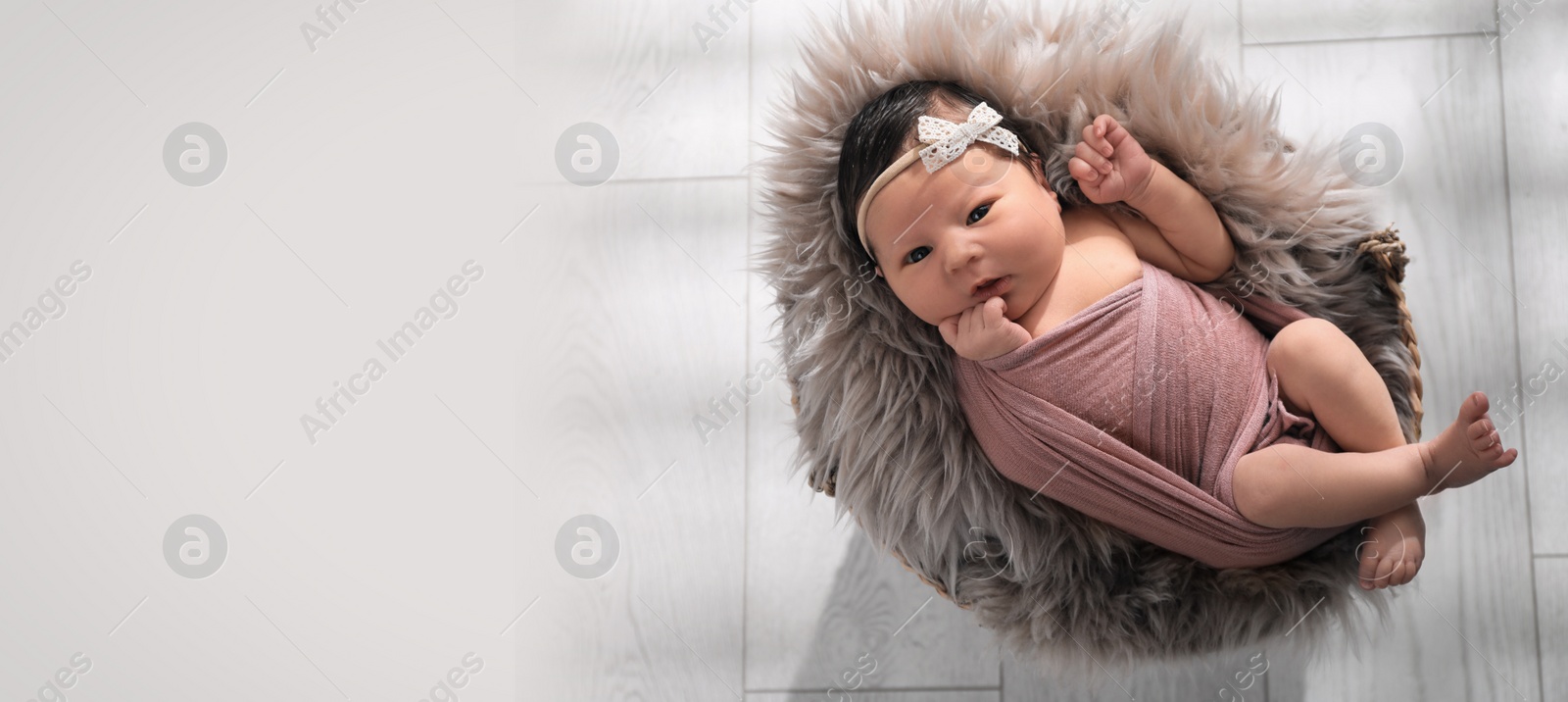 Image of Cute newborn baby lying in wicker basket, top view with space for text. Banner design