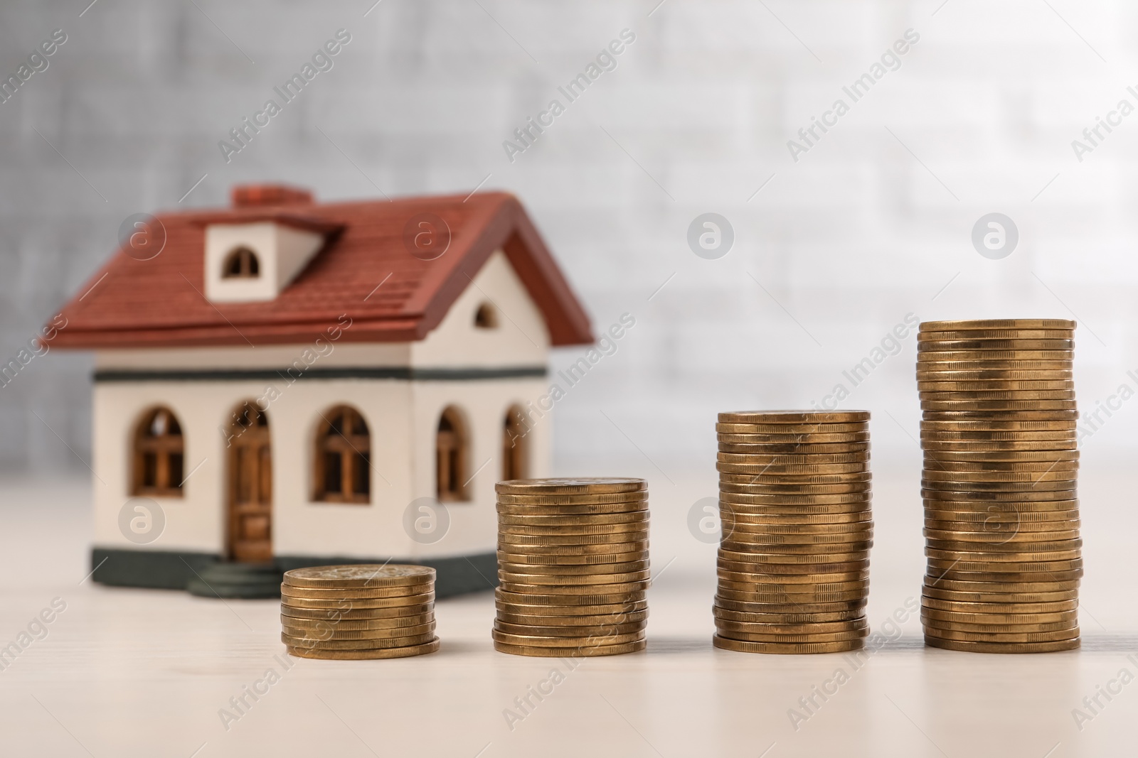 Photo of Mortgage. Stacked coins and house model on light table