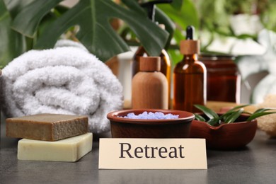 Photo of Card with word Retreat and different spa products on grey table