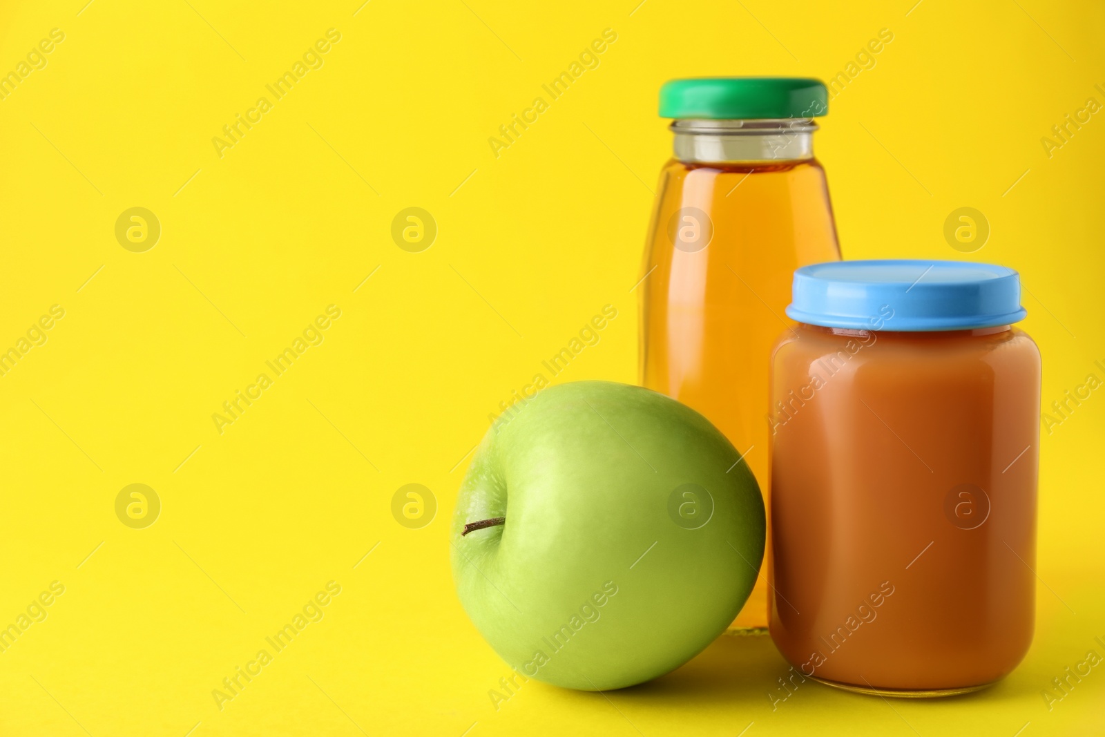 Photo of Healthy baby food, juice and apple on yellow background, space for text