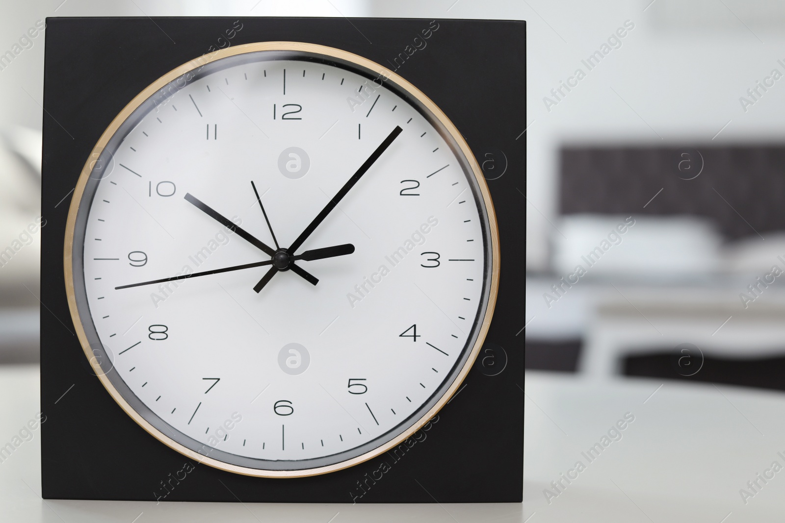 Photo of Analog alarm clock on table in bedroom, closeup. Time of day