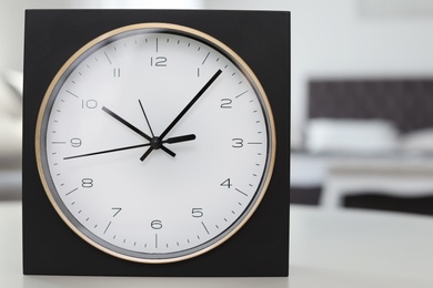 Analog alarm clock on table in bedroom, closeup. Time of day