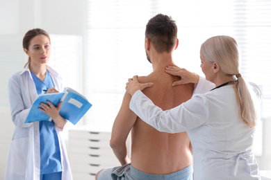 Female orthopedist examining patient's back in clinic