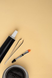 Photo of Flat lay composition with eyebrow henna and tools on beige background. Space for text