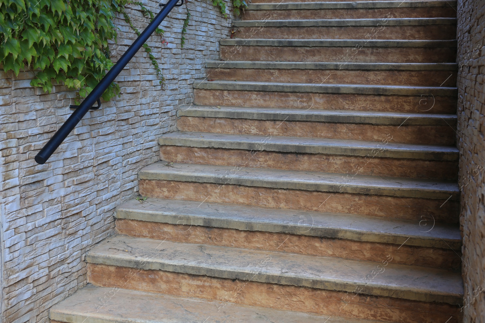 Photo of View of beautiful old stairs near brick wall with climber plant outdoors