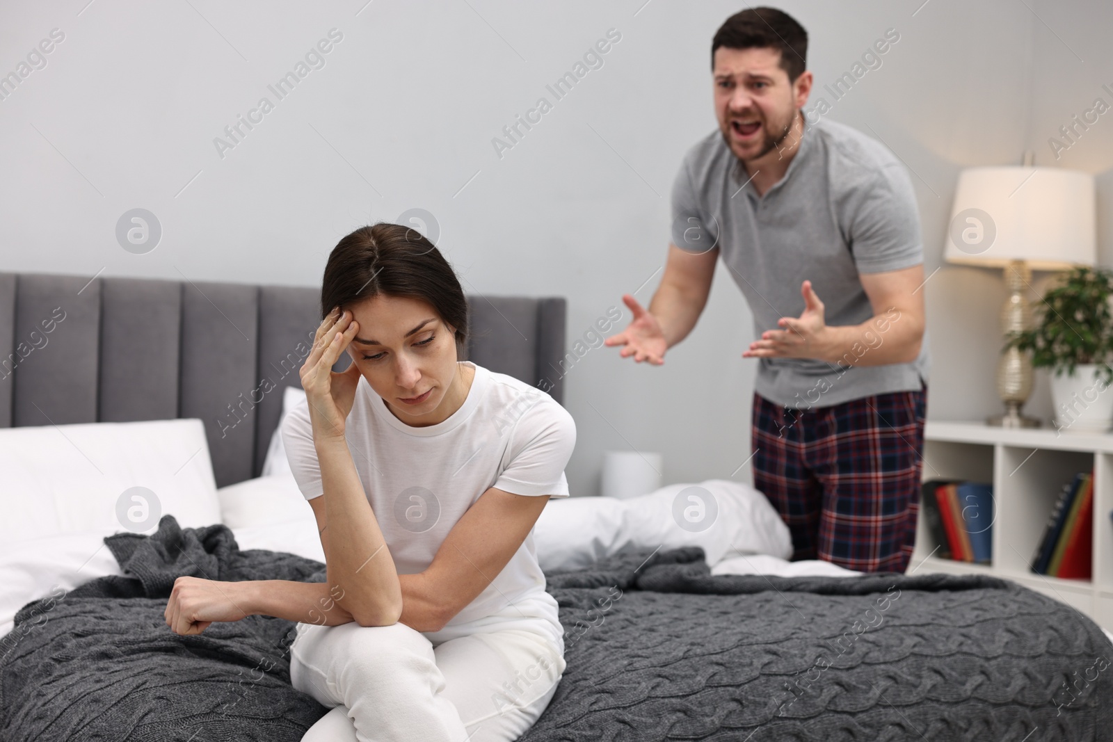 Photo of Offended wife ignoring her angry husband in bedroom, selective focus. Relationship problems