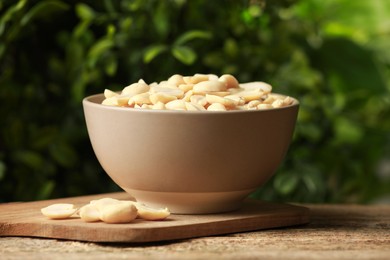 Photo of Fresh peanuts in bowl on wooden table against blurred background