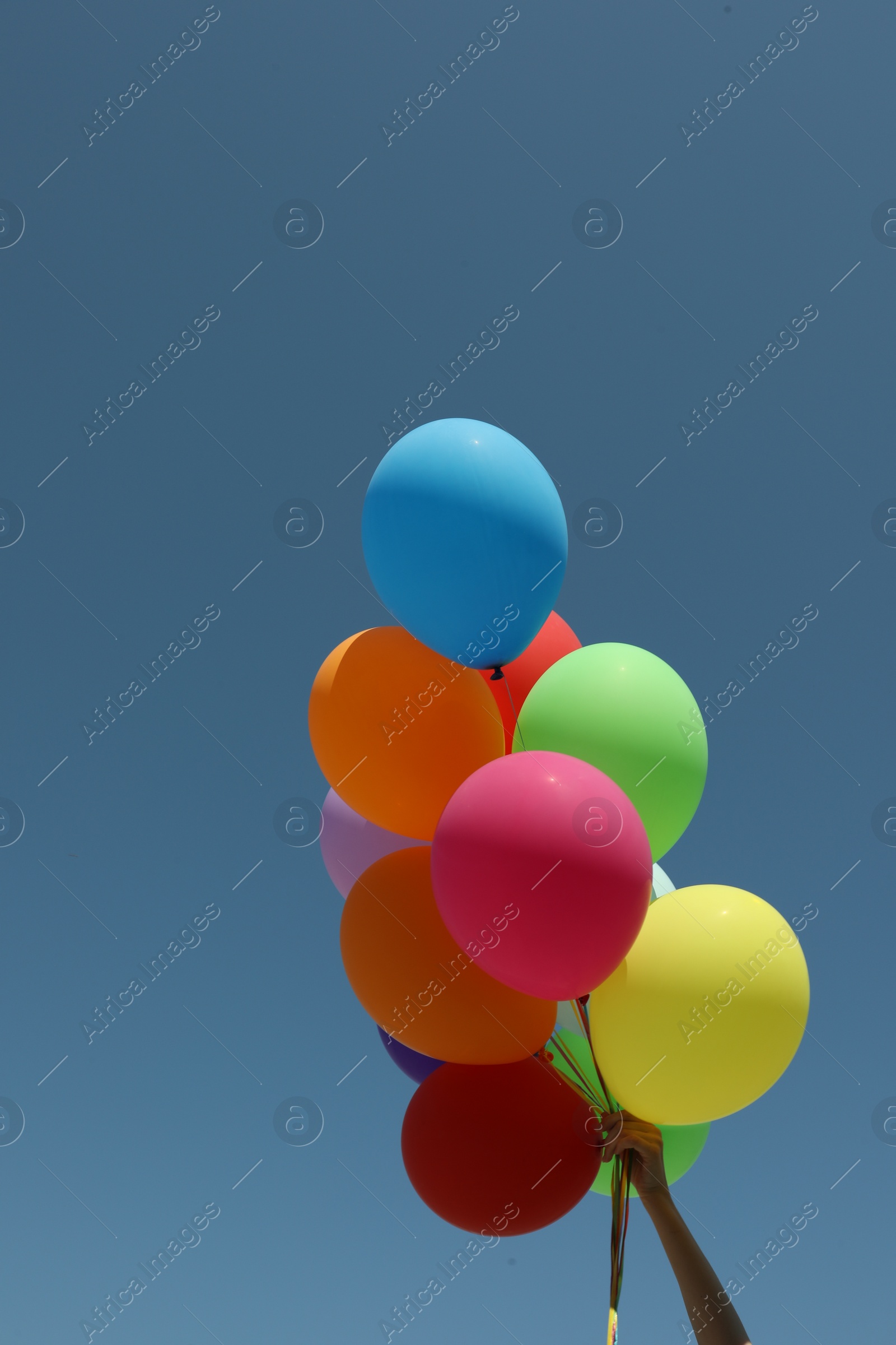 Photo of Woman with bunch of colorful balloons against blue sky, closeup