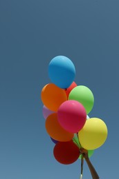 Woman with bunch of colorful balloons against blue sky, closeup