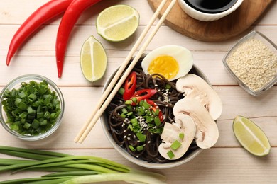 Photo of Flat lay composition with tasty buckwheat noodles (soba) and chopsticks on wooden table