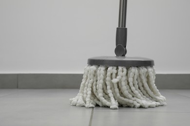 Photo of Cleaning grey tiled floor with string mop, closeup. Space for text