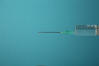 Photo of Medical syringe on light blue background, closeup. Space for text