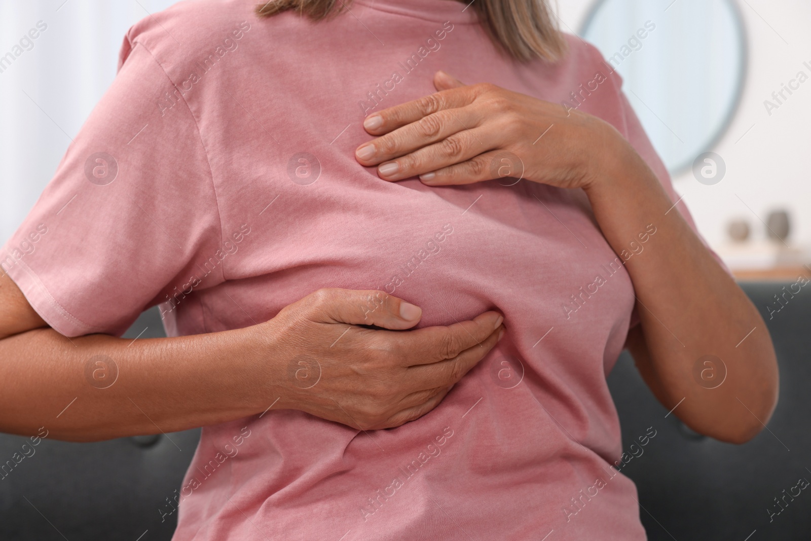 Photo of Woman doing breast self-examination at home, closeup