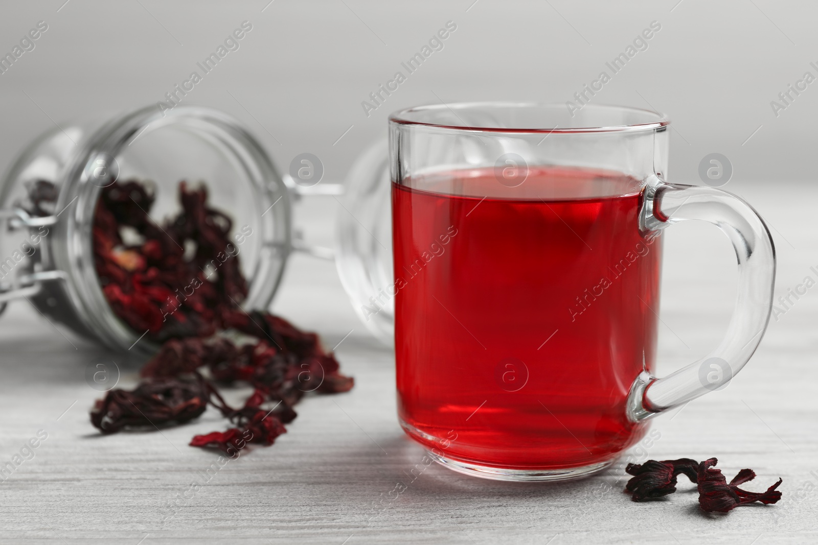 Photo of Delicious hibiscus tea and dry flowers on white wooden table, space for text