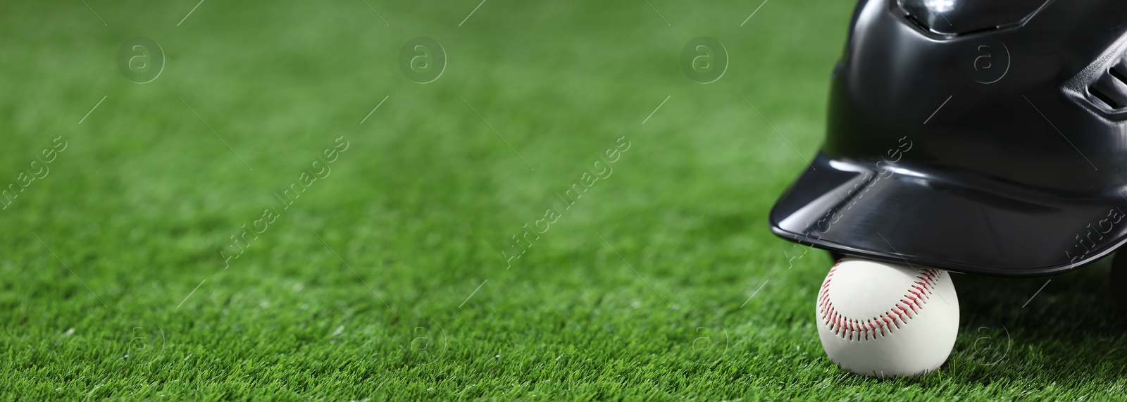 Image of Batting helmet and baseball ball on green grass, space for text. Banner design