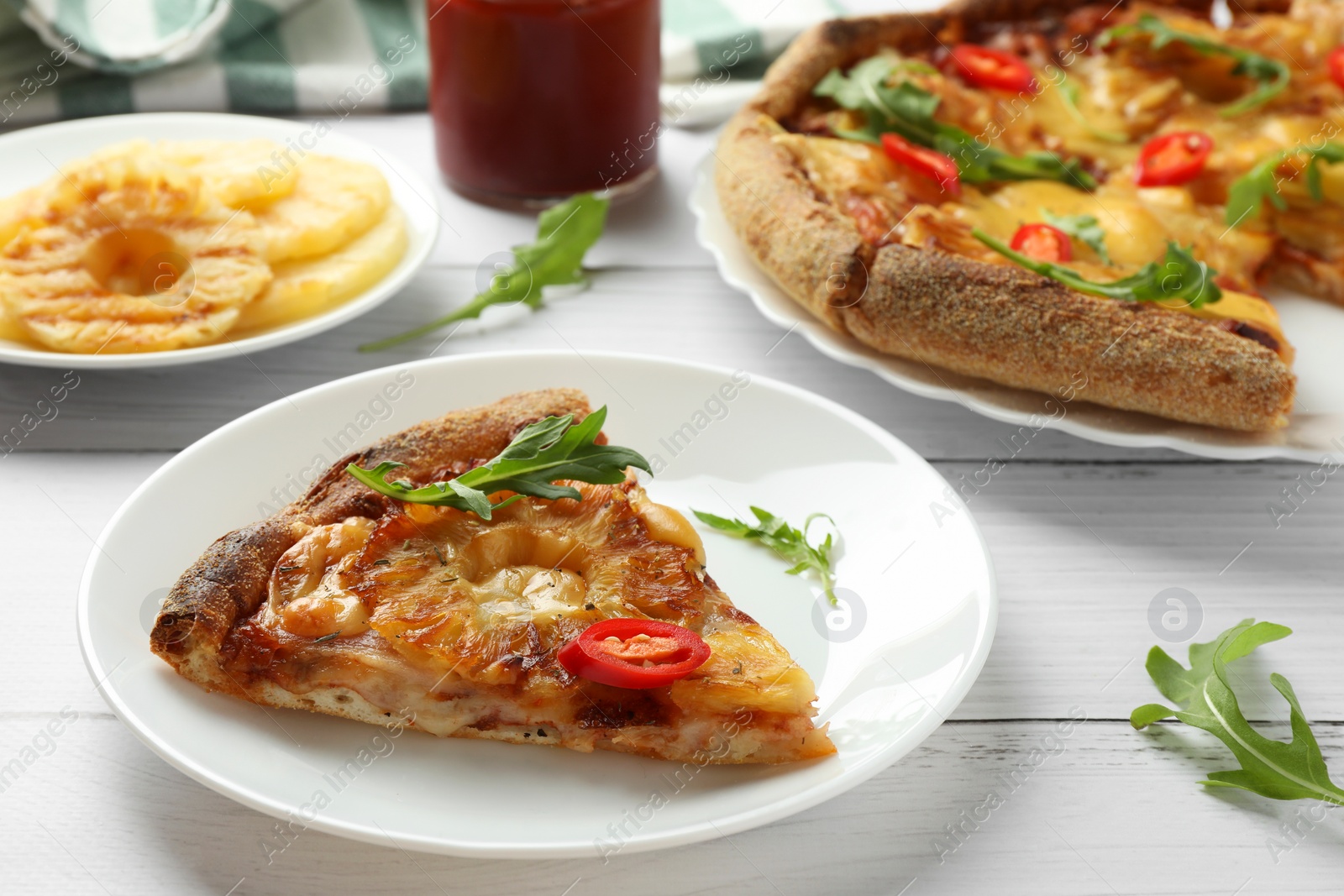 Photo of Plate with piece of delicious pineapple pizza on white wooden table