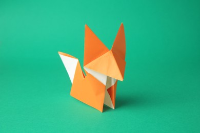 Photo of Origami art. Handmade orange paper fox on green background