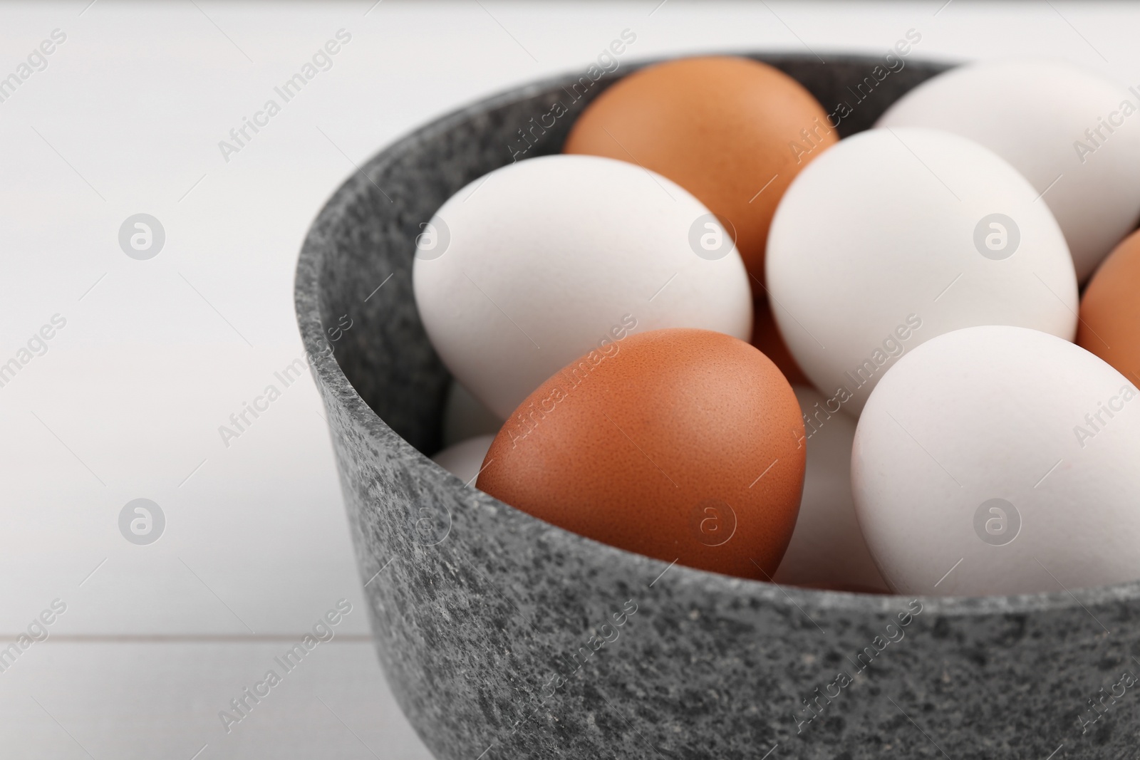 Photo of Unpeeled boiled eggs in saucepan on white table, closeup. Space for text