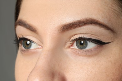 Young woman with beautiful eyebrows on grey background, closeup