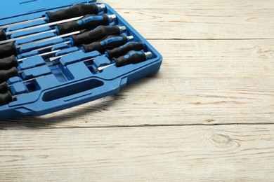 Photo of Set of screwdrivers in open toolbox on light wooden table. Space for text