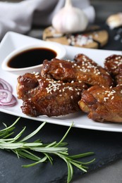 Chicken wings glazed with soy sauce served on table, closeup