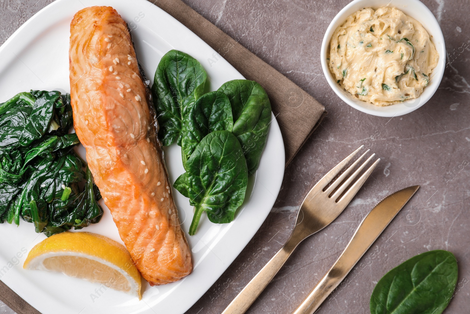 Photo of Tasty salmon with spinach and lemon served on marble table, flat lay