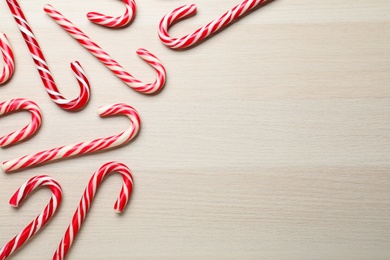 Sweet Christmas candy canes on wooden background, flat lay. Space for text