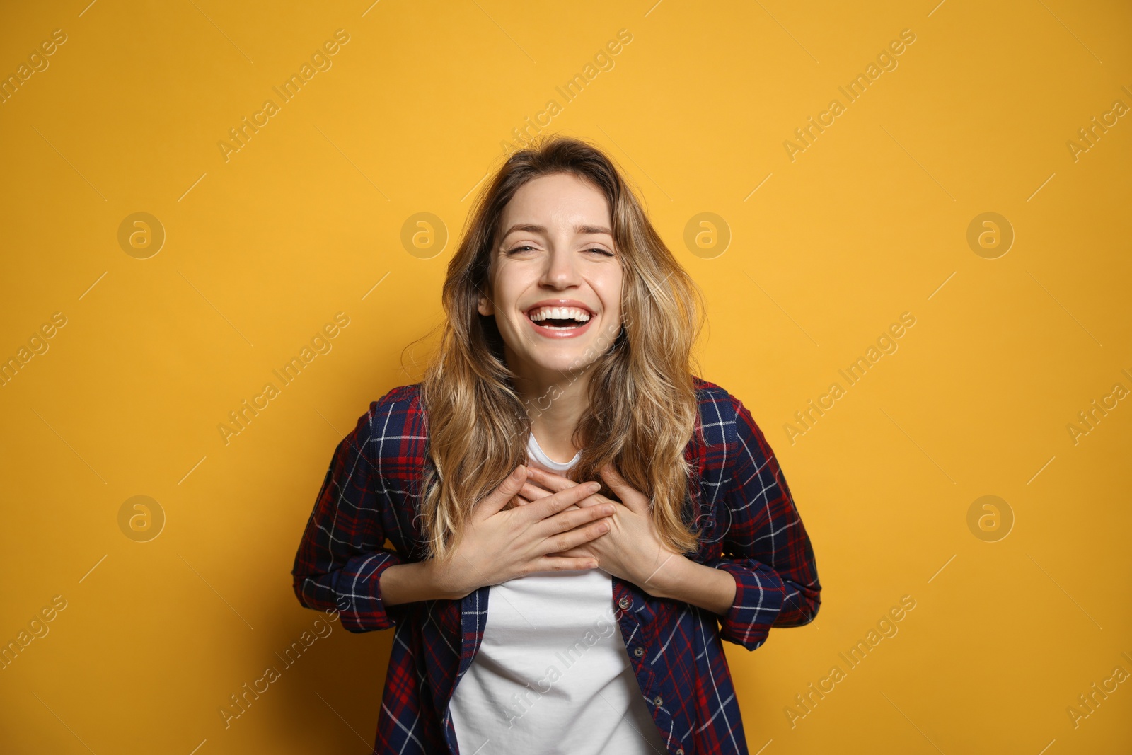 Photo of Cheerful young woman laughing on yellow background