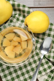 Delicious quince drink in glass bowl, fresh fruits and spoon on wooden table, top view