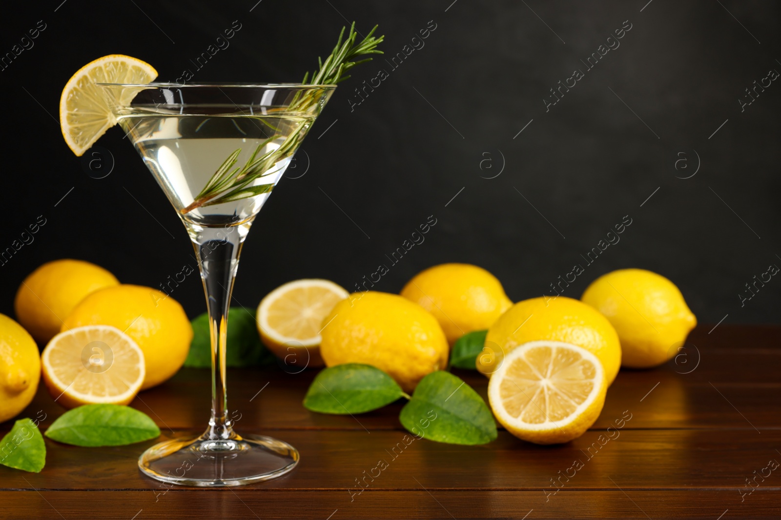 Photo of Martini cocktail with lemon slice and fresh fruits on wooden table, space for text