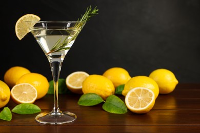 Martini cocktail with lemon slice and fresh fruits on wooden table, space for text