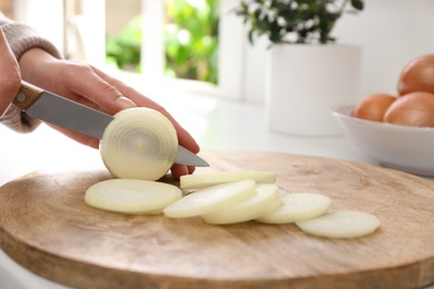Photo of Woman cutting white onion into rings at countertop, closeup