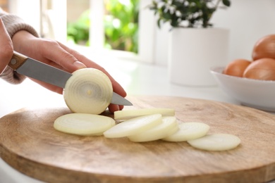 Woman cutting white onion into rings at countertop, closeup