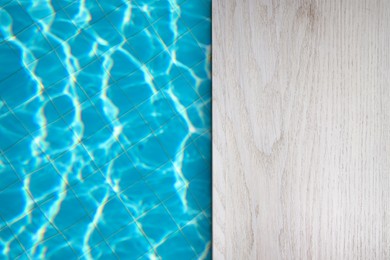 Image of Empty white wooden surface near swimming pool with clear water. Space for design