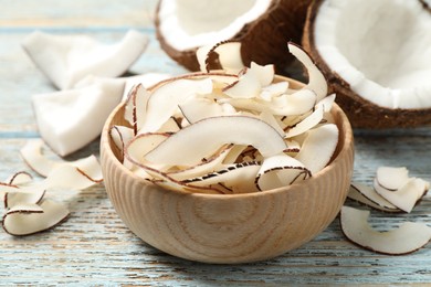 Photo of Tasty coconut chips on light blue wooden table