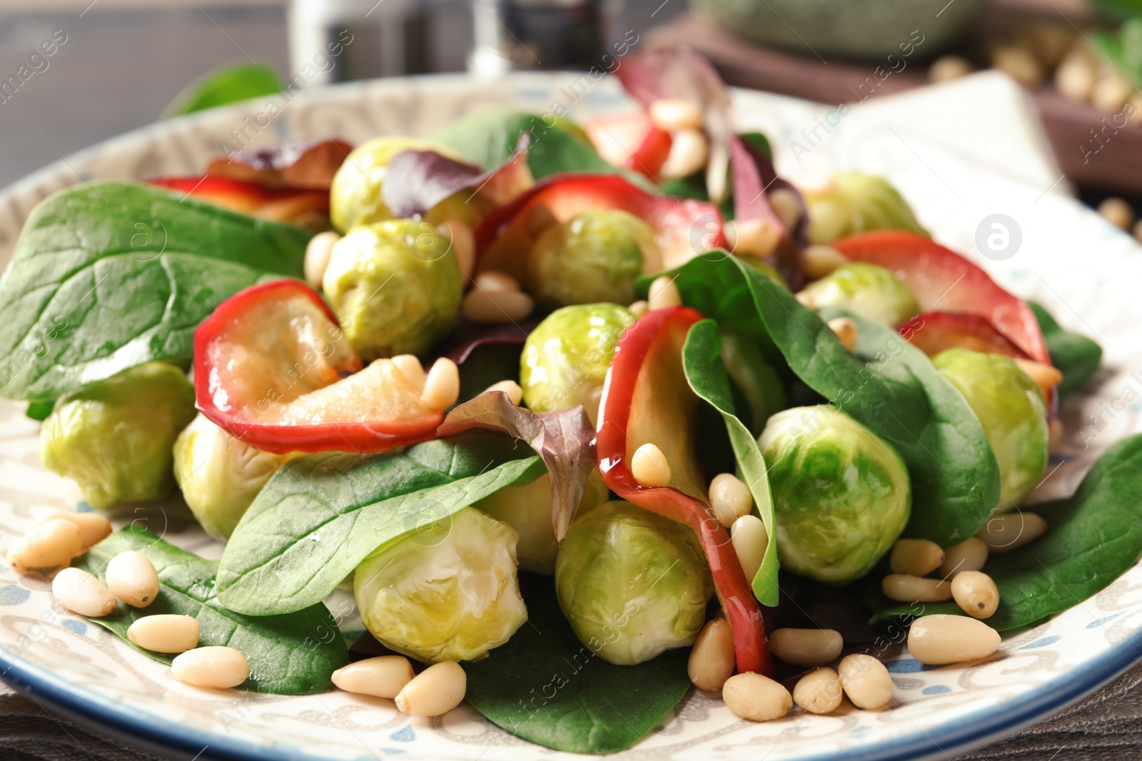 Photo of Delicious salad with Brussels sprouts and roasted apples on plate, closeup