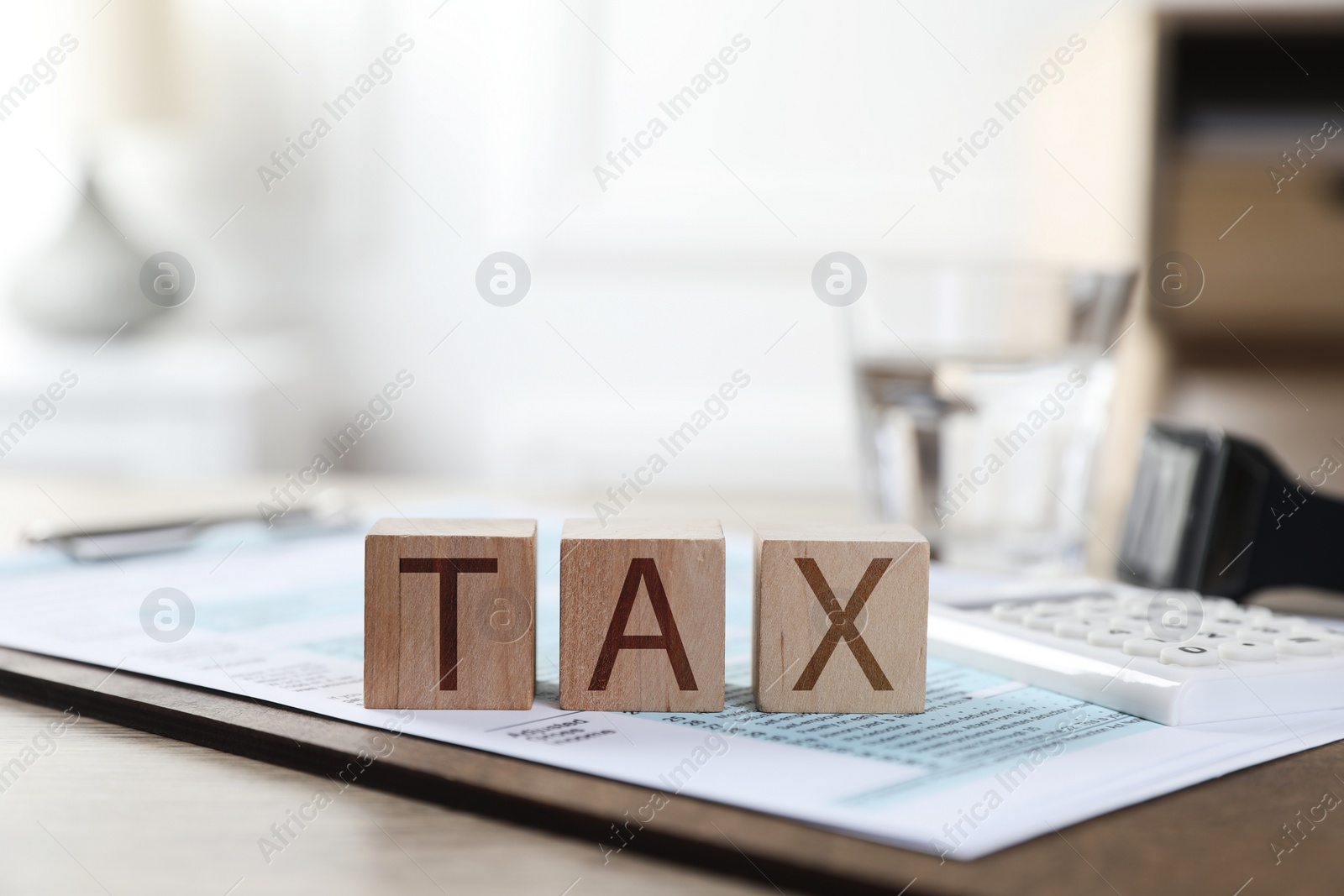 Photo of Wooden cubes with word Tax and document on table, closeup