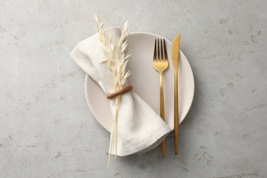 Stylish setting with cutlery, napkin, dry branch and plate on light table, top view