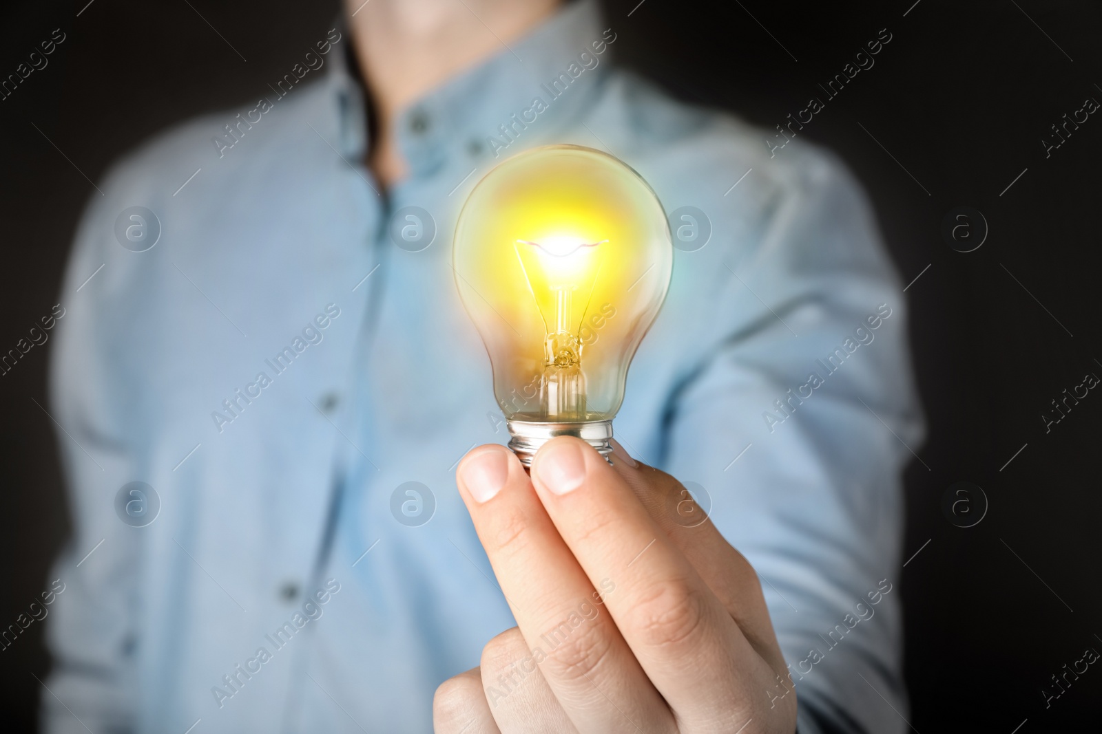 Image of Glow up your ideas. Man holding light bulb on black background, closeup